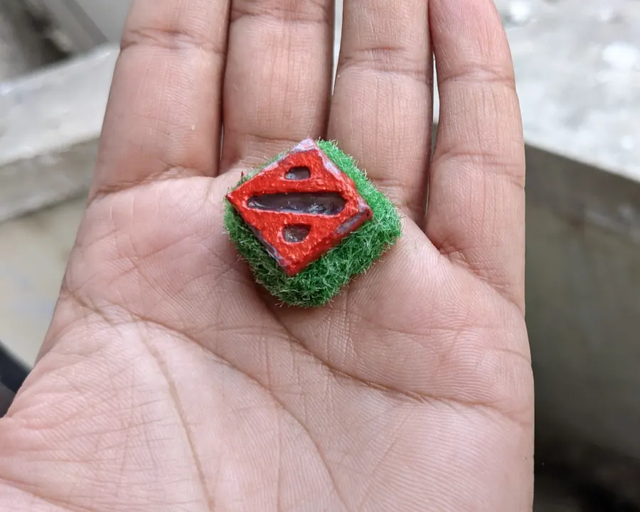A small red and green keycap held in the palm of a hand
