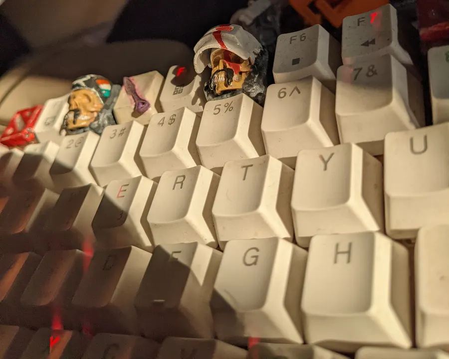 A white keyboard with several hand-painted artisan keycaps on its keys